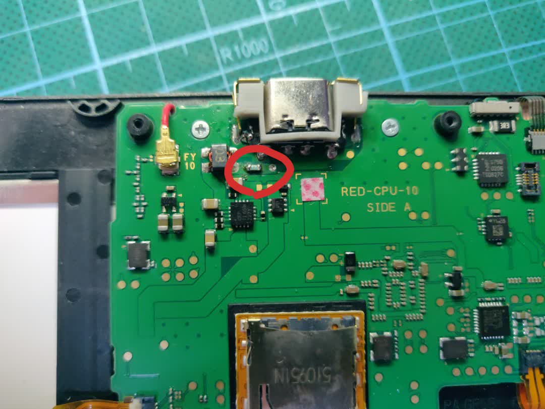 Close-up picture of
		the top of the main board on a new 3DS XL. The newly installed fuse is
		visible and circled in red.