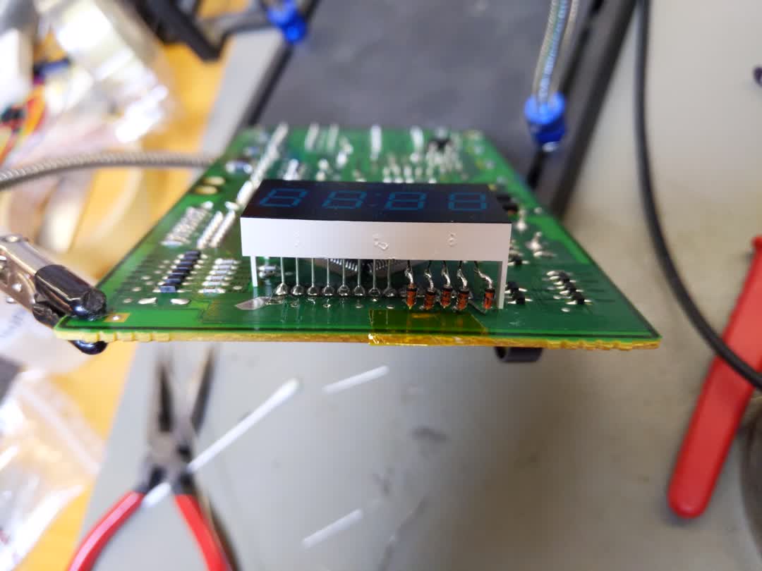 Picture of the
  microwave mainboard completely removed from the microwave. The LCD unit can
  be seen on top of the board, and the newly soldered-in diodes can also be
  seen.