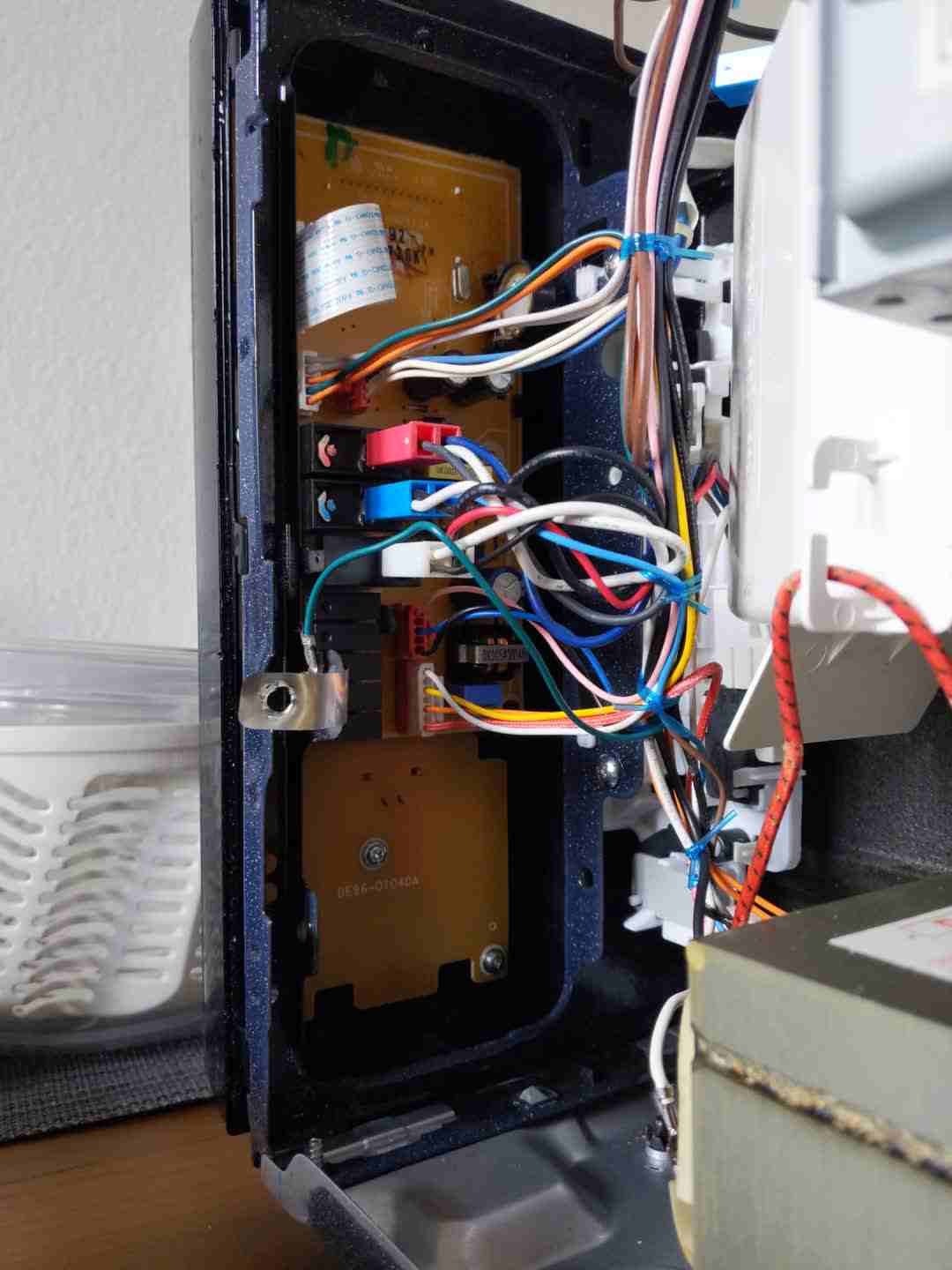 Internals of a partially
  disassembled microwave. The mainboard to which the LCD screen and all the
  buttons are attached can be seen, as well as the different cables and
  connectors that connect to the board.